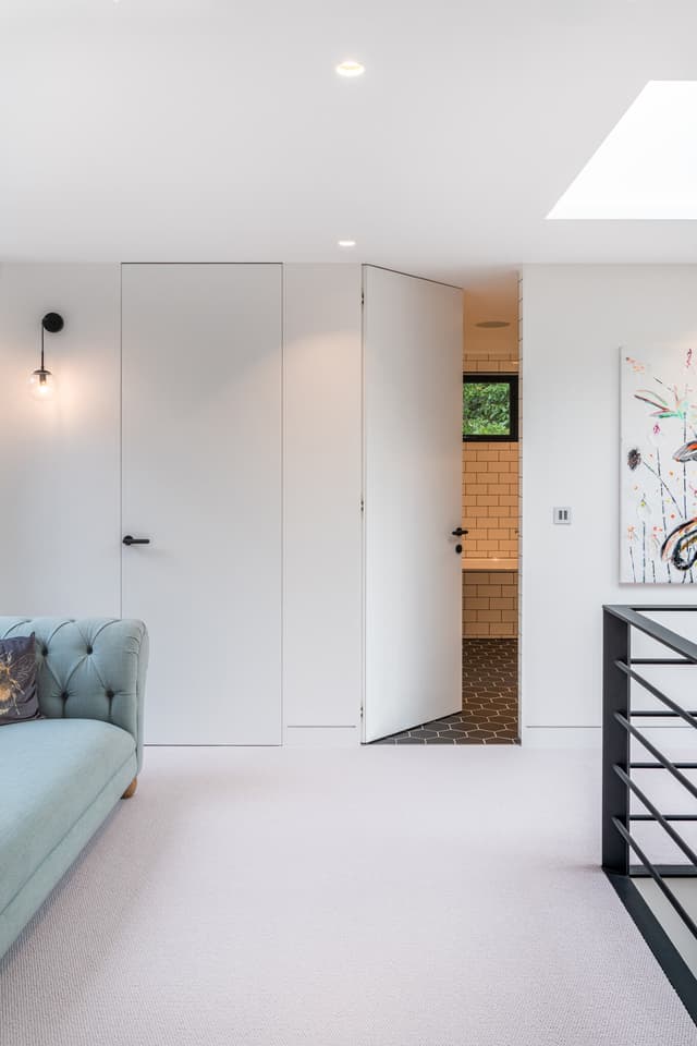 A carpeted landing area with two flush single doors, one open and leading into a tiled bathroom.