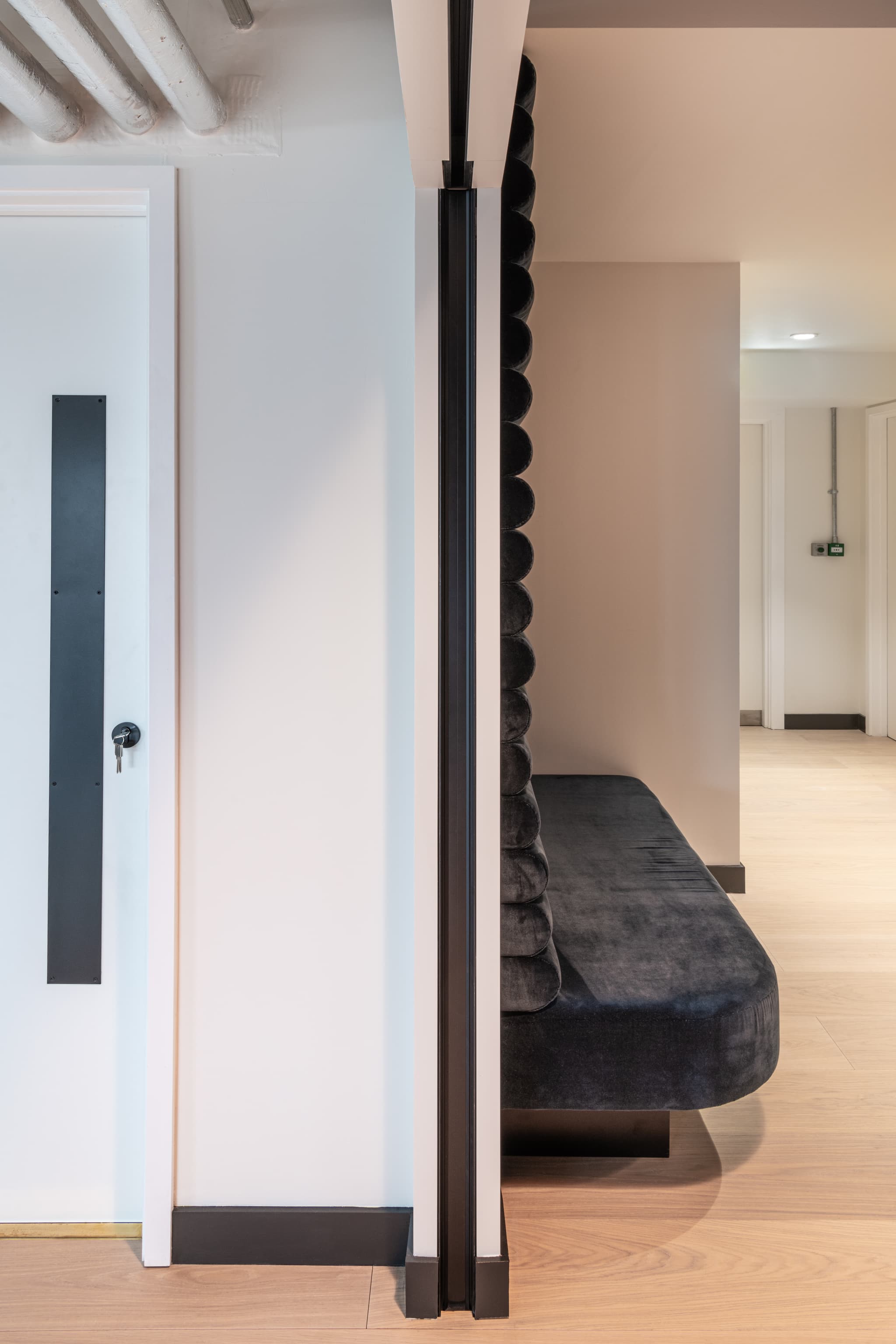 Black slam post of a sliding pocket door system in a white office interior with black velvet sofa to the right.