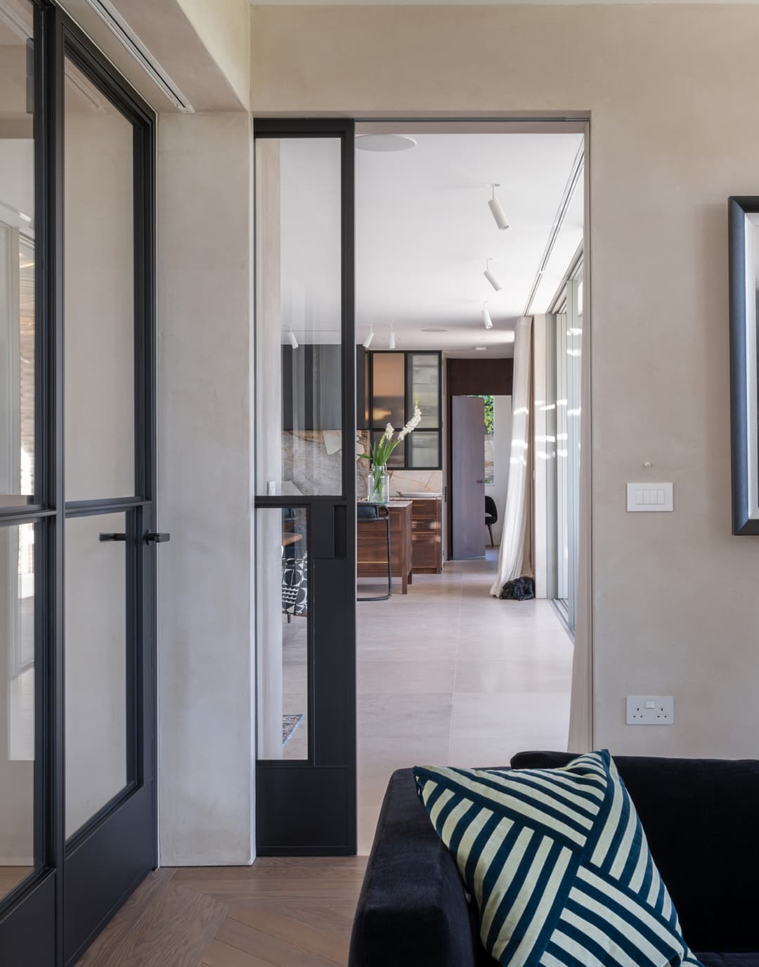 sliding steel glazed door in black leading to an open plan kitchen dining room