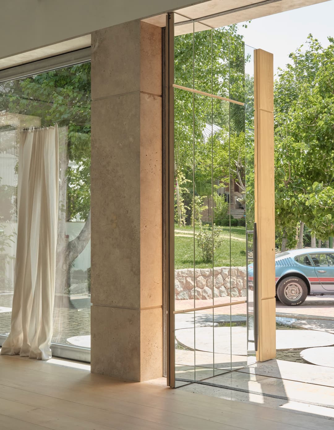 an external pivot door with reflective glass, clear glass and oak using FritsJurgens System M+