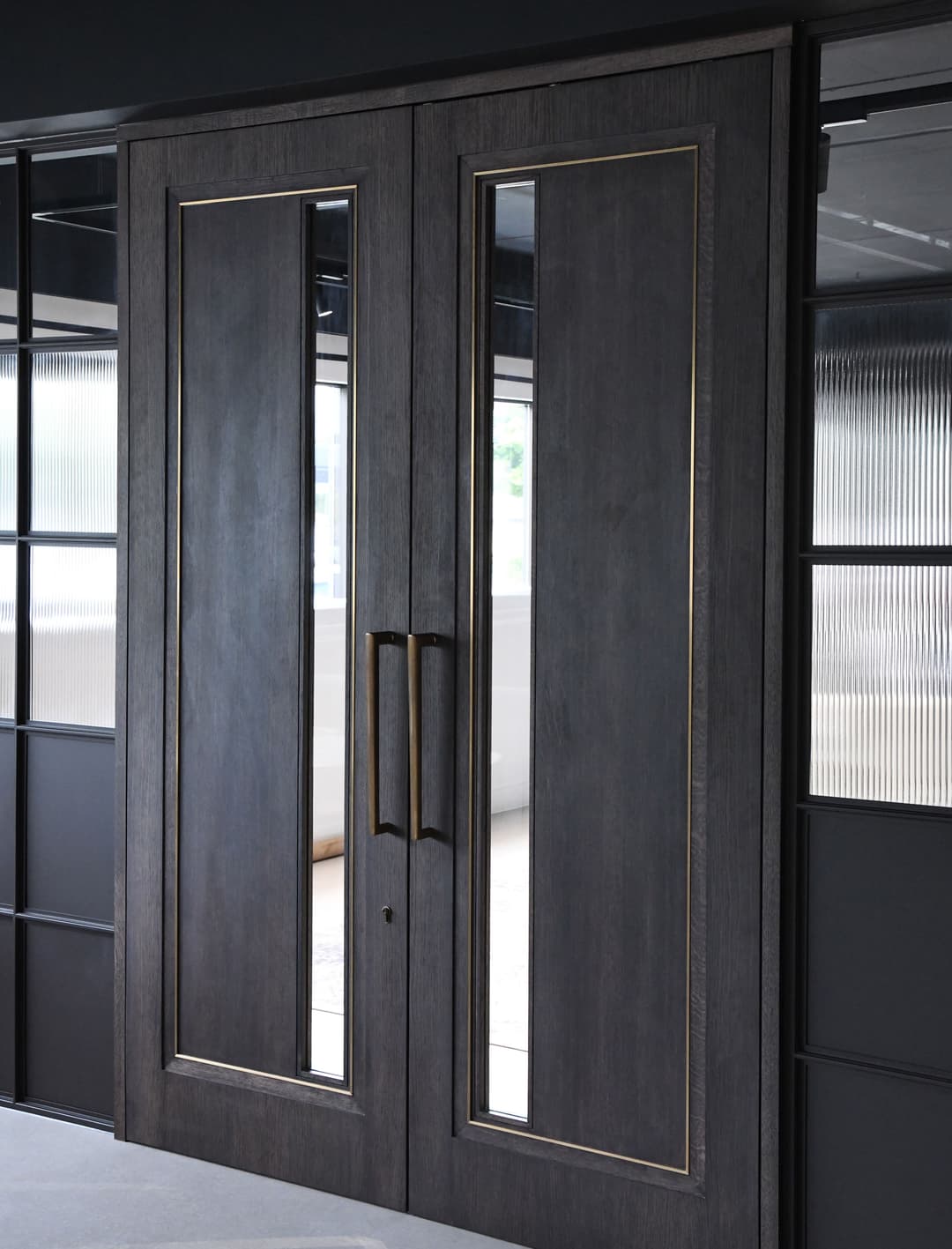 a double timber doorset with glass panels and gold metal inlay with large pull handles